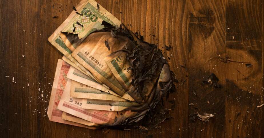 Scorched banknotes scattered on a dark surface symbolising the financial losses of Grofers marketing strategy in India before its rebrand to Blinkit