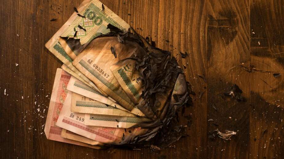 Scorched banknotes scattered on a dark surface symbolising the financial losses of Grofers marketing strategy in India before its rebrand to Blinkit